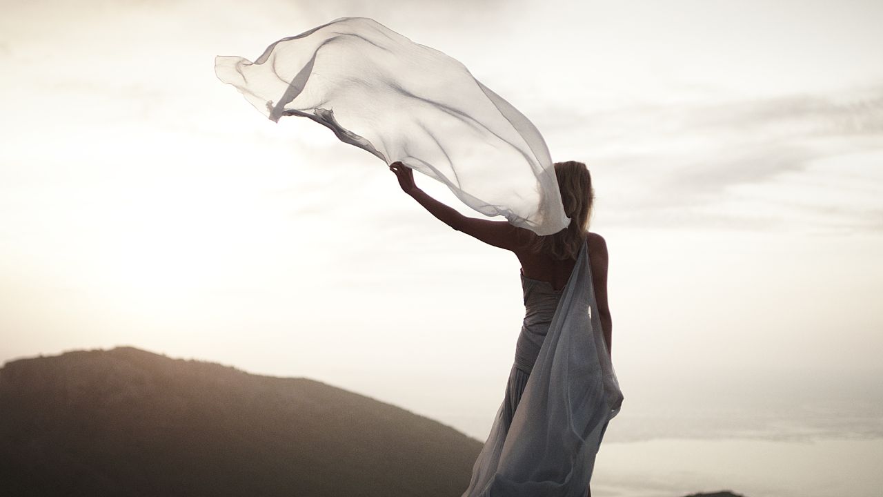 woman in yellow dress standing on brown sand under blue sky during daytime